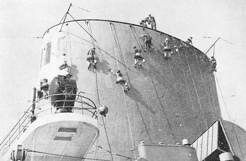 CLEANERS AT WORK on the funnels of one of the great German liners